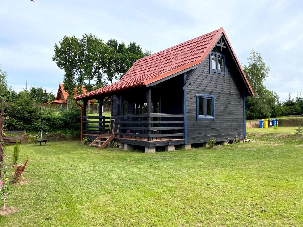 een klein huis met een rood dak op een erf bij Mazurska Zagroda Domek Letniskowy in Rydzewo
