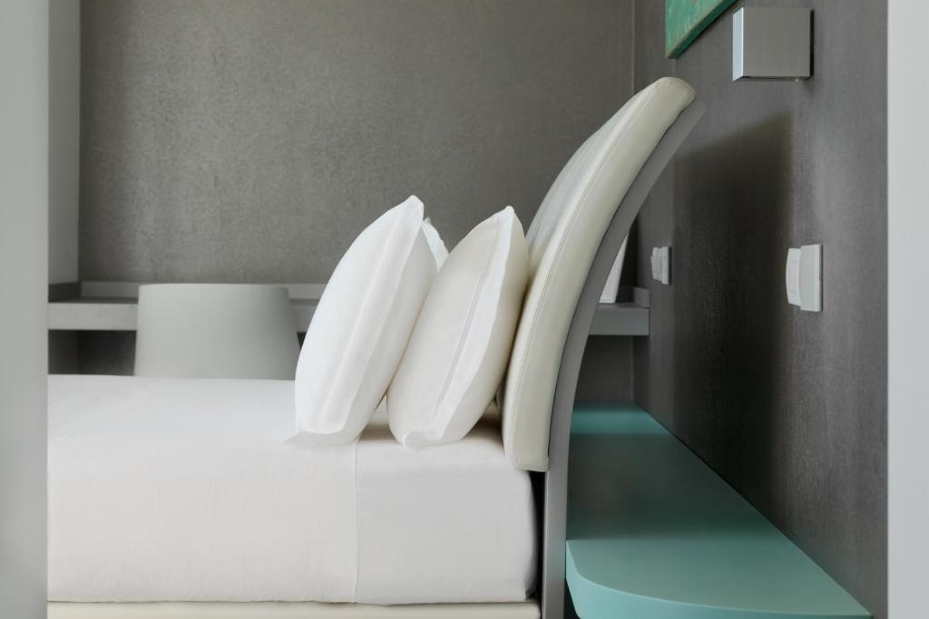 a bed with white pillows on it in a room at Life Hotel Seaview & Spa in Porto Recanati