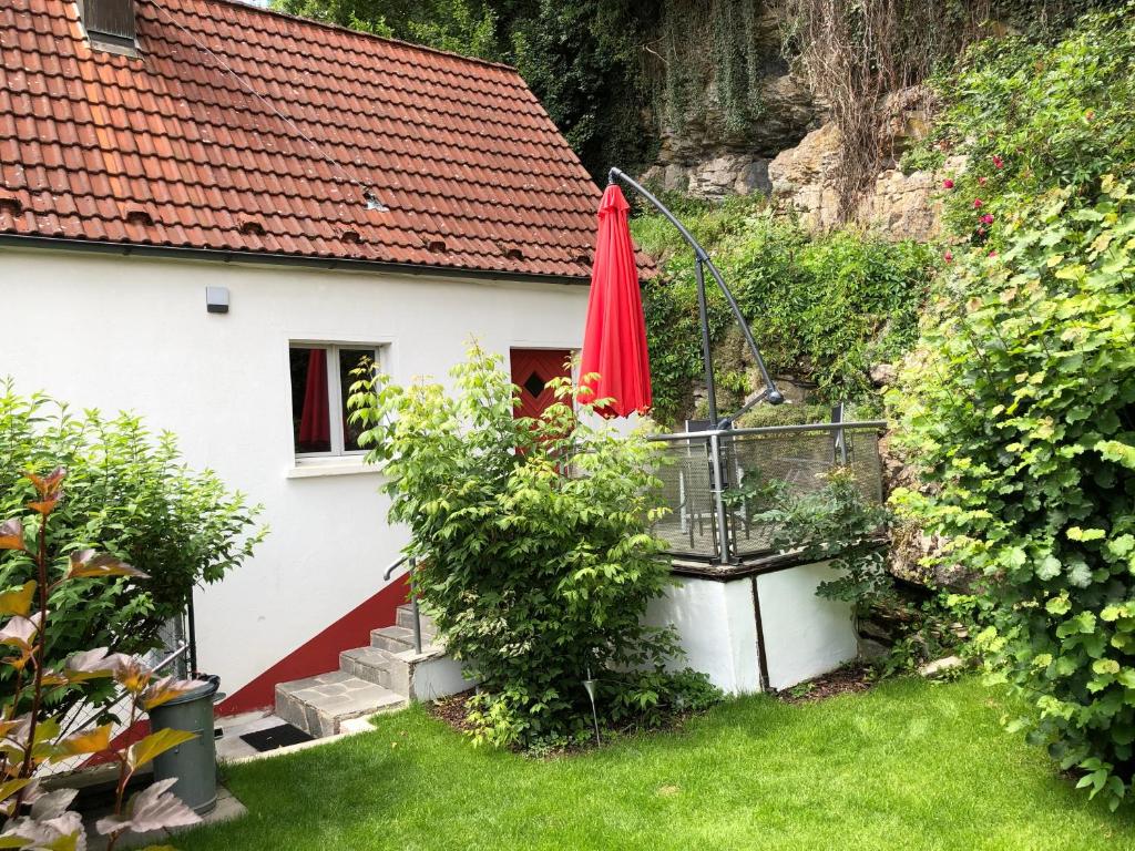 una casa blanca con un paraguas rojo en el patio en Ferienhaus Heinrich, en Egloffstein