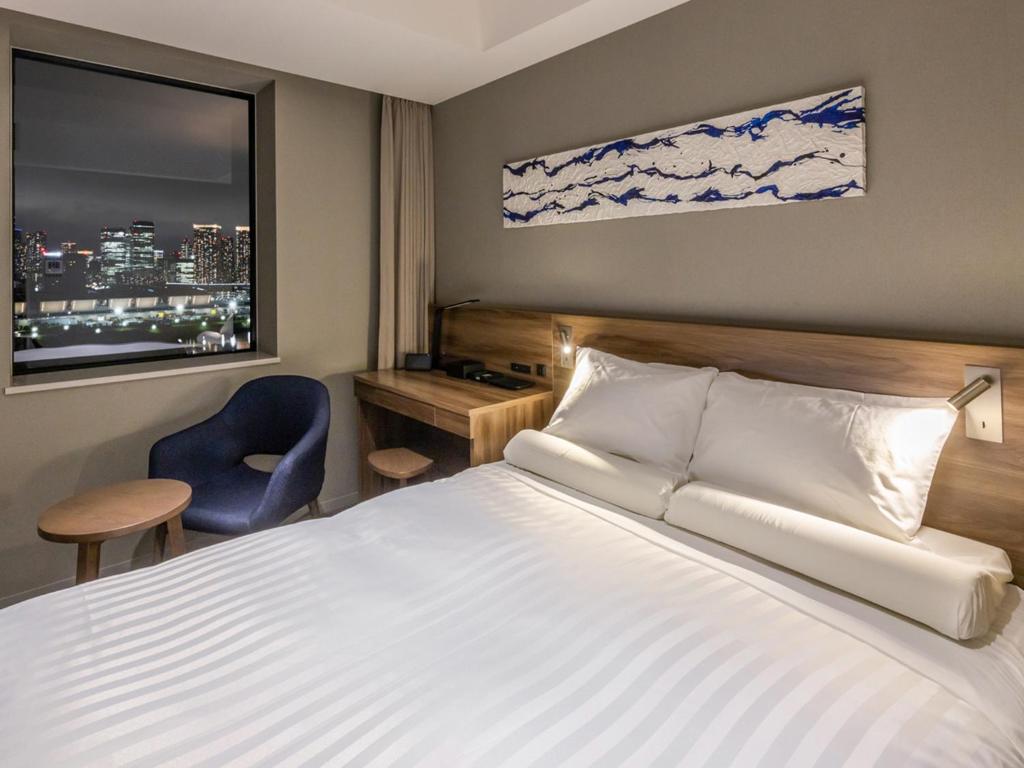 ein Hotelzimmer mit einem Bett, einem Stuhl und einem Fenster in der Unterkunft Far East Village Hotel Tokyo Ariake in Tokio