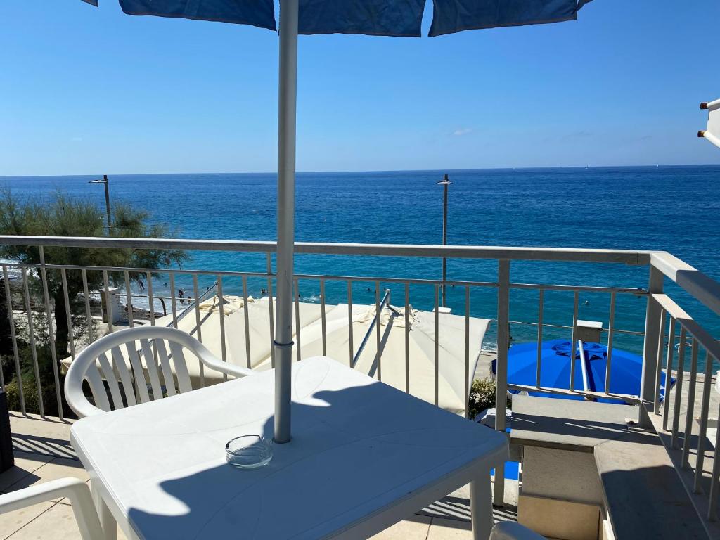 a table with an umbrella on a balcony with the ocean at Caravella in Deiva Marina