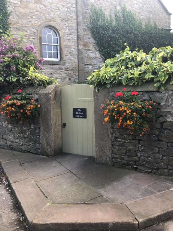 a white door in a stone wall with flowers at The Hollow Bed and Breakfast in Great Longstone