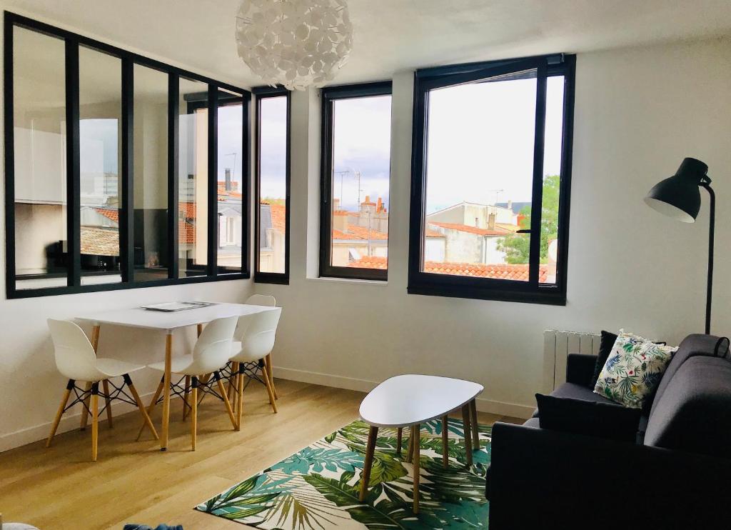 a living room with a table and chairs and windows at Appartement Saint-Nicolas in La Rochelle