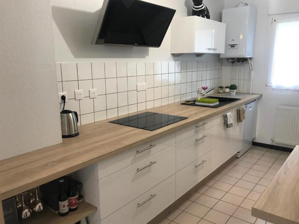 une cuisine avec des armoires blanches et un comptoir dans l'établissement La maison de ville - 4 chambres, 2 sdb, terrasse et garage - 90m2, à Vesoul