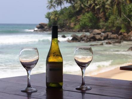 a bottle of wine sitting on a table with two glasses at Coral Beach Hotel in Mirissa