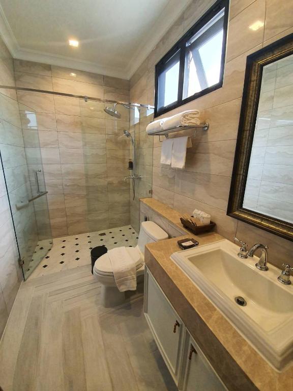 A compact tiled bathroom with a glass-enclosed walk-in shower, toilet and vanity.