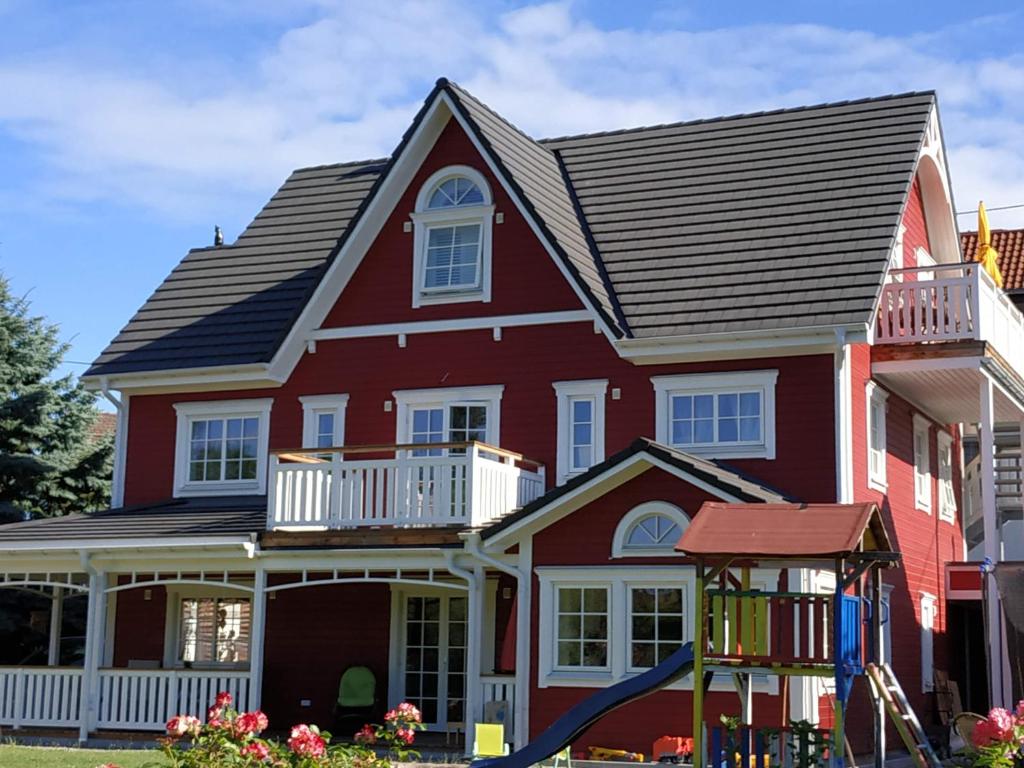 ein rotes Haus mit einem Spielplatz davor in der Unterkunft Ferienwohnung Kleiner Onkel in Uhldingen-Mühlhofen