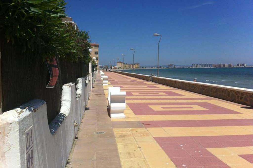 rząd ławek na ścianie obok oceanu w obiekcie La manga arriba w mieście La Manga del Mar Menor
