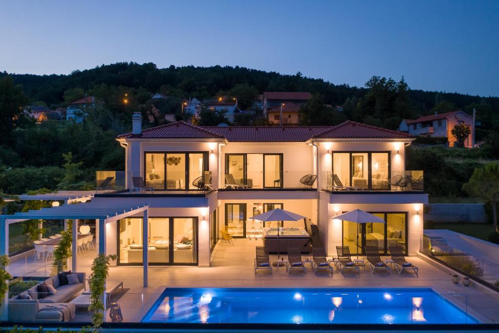 a large house with a swimming pool at night at Villa Elegance in Sinj