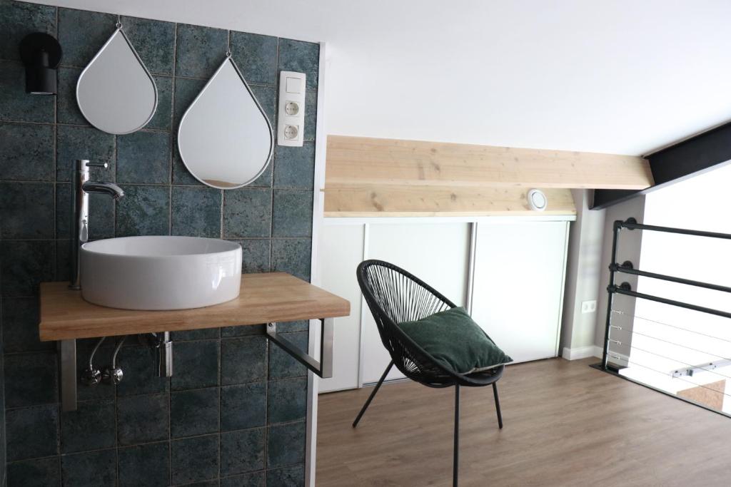 een badkamer met een wastafel en 2 spiegels aan de muur bij Met de Kippen op Stok - Vakantiehuisjes in Baexem