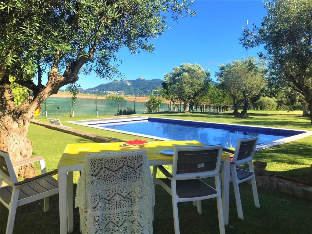 un tavolo con sedie di fronte alla piscina di Villa das Oliveiras a Sintra