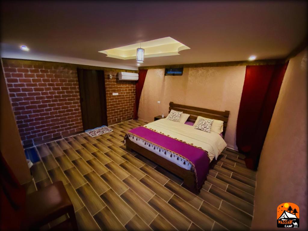 1 dormitorio con cama y pared de ladrillo en Petra Wassaif Camp, en Wadi Musa