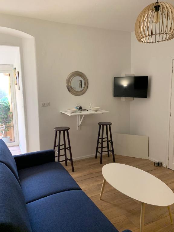 - un salon avec un canapé bleu, une table et un tabouret dans l'établissement Studio terrasse rue piétonne Ajaccio, à Ajaccio