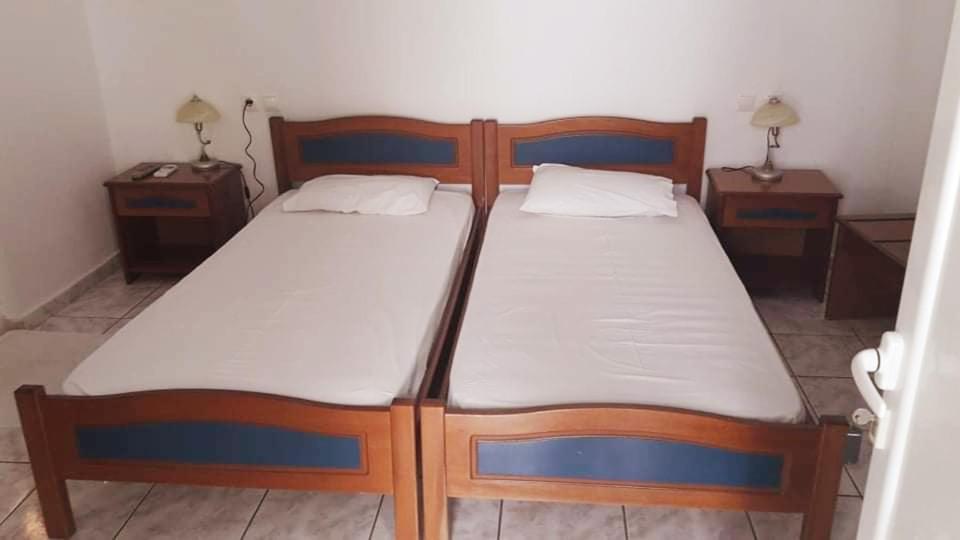 a bedroom with two wooden beds and two night stands at Theofilos Appartements in Livadi