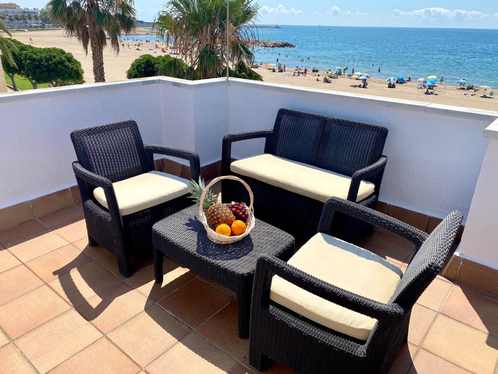 a balcony with chairs and a table with a bowl of fruit at Casa cómoda delante de la playa con vista al mar in Cambrils