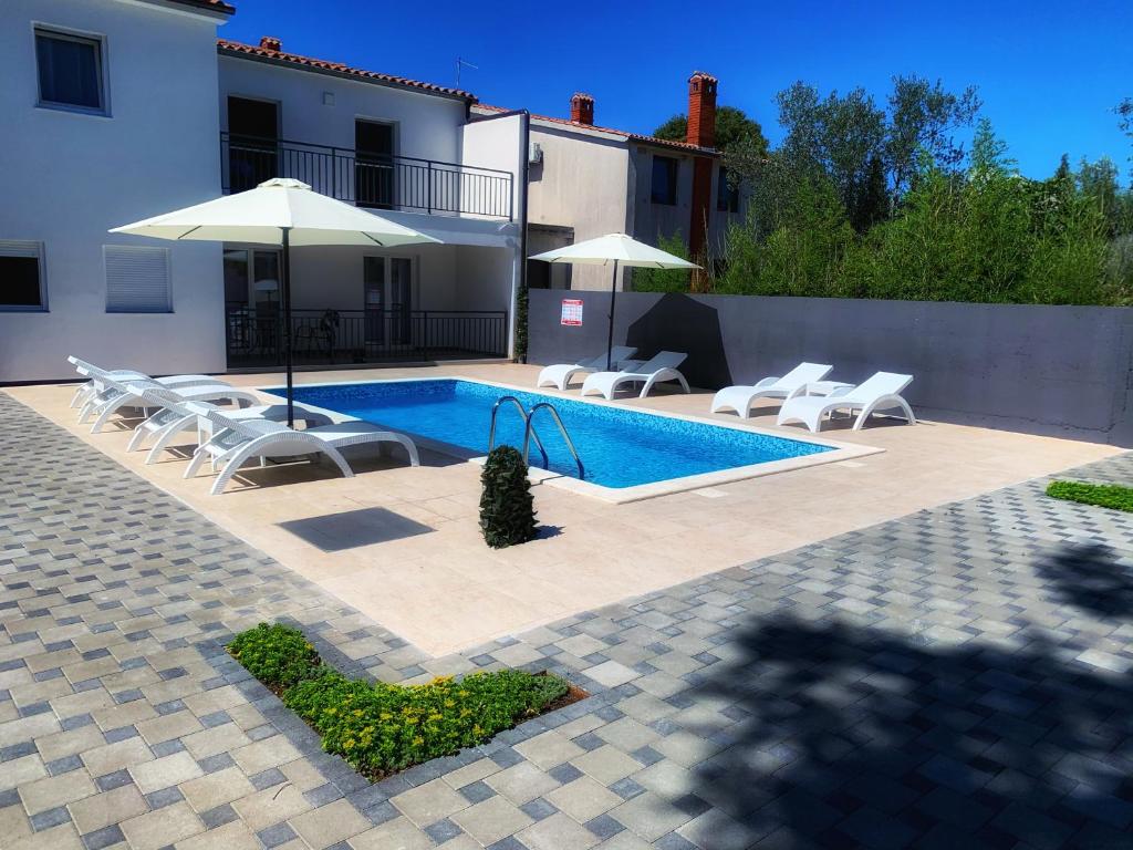 a swimming pool with chairs and an umbrella next to a house at Villa Lord in Pomer