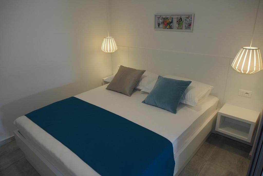 1 dormitorio con 1 cama con almohadas azules y blancas en Vila Snježana Tučepi, en Tučepi