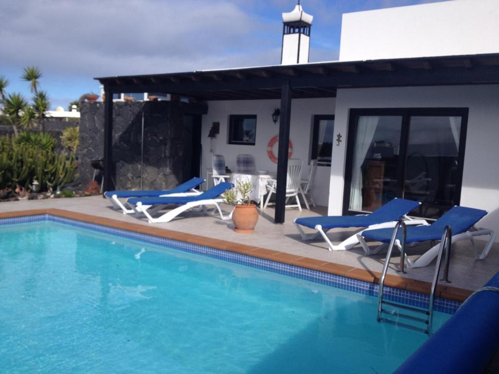 a swimming pool with chairs and a house at Villa Burgao in Playa Blanca