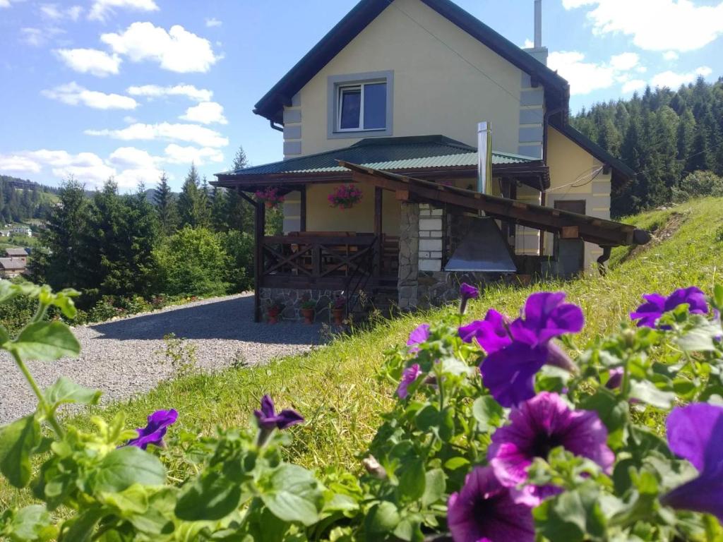 una casa con fiori viola di fronte di Котедж "Зорі Карпат" a Slavske