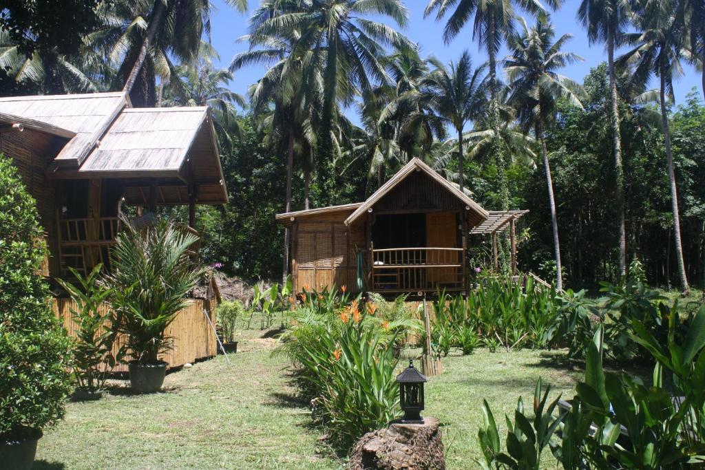 a house in a garden with palm trees in the background at Kuba Bungalows in Ko Kood