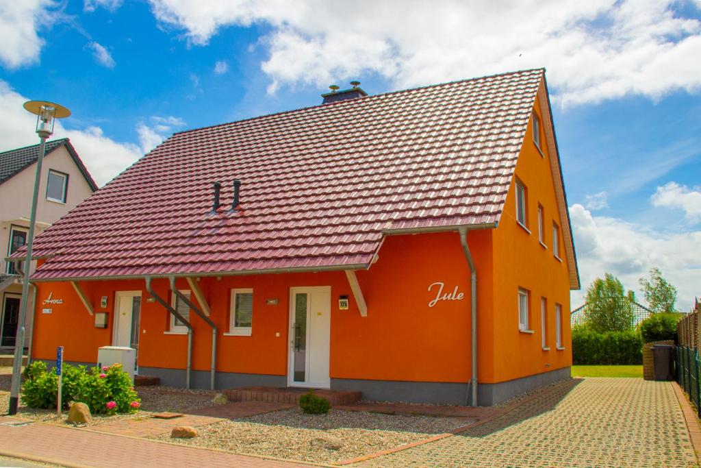 una casa naranja con techo rojo en Ferienhaus Nienhagen - Jule, en Ostseebad Nienhagen