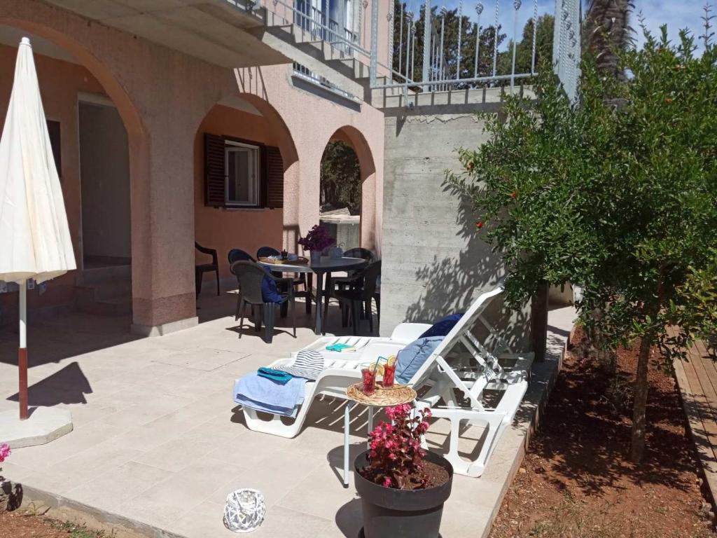 eine Terrasse mit einem Tisch, Stühlen und einem Sonnenschirm in der Unterkunft Apartment Ilovik 154 - 3 bedroom in Ilovik