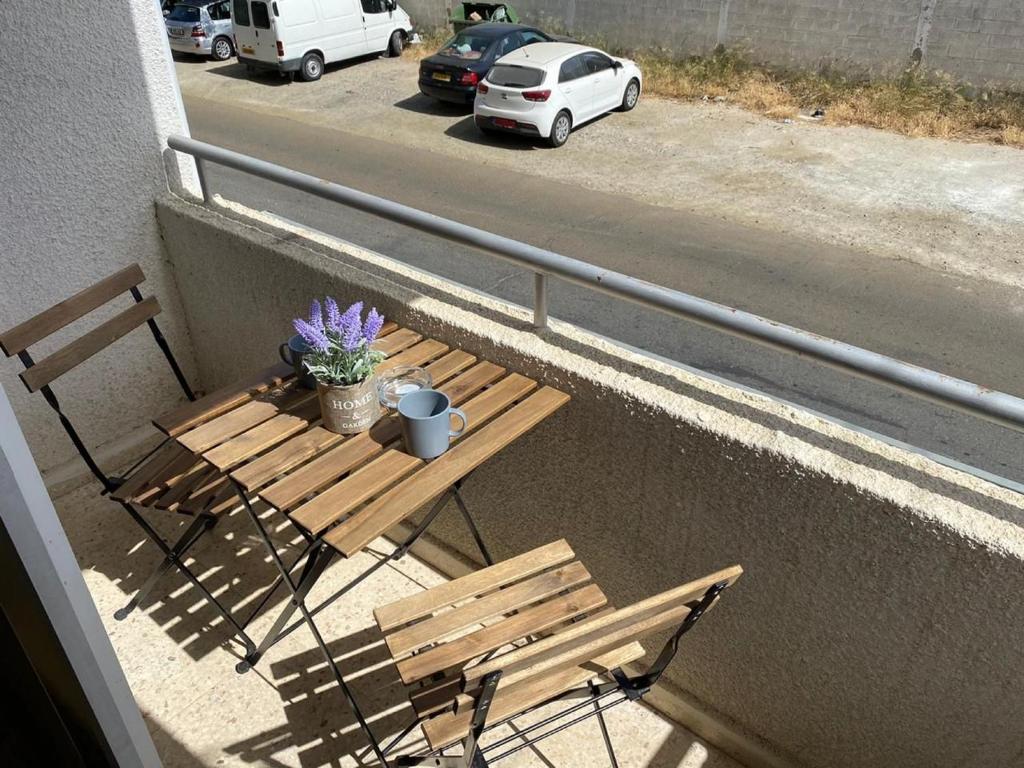 a wooden table and chair on a balcony with a table and flowers at Comfort Apartment in Larnaca
