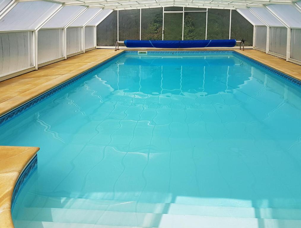 - une grande piscine sous un chapiteau d'eau bleue dans l'établissement Stone cottage with modern cosy interior near to Josselin Perfect retreat for Writers or Star Gazers, à Guégon
