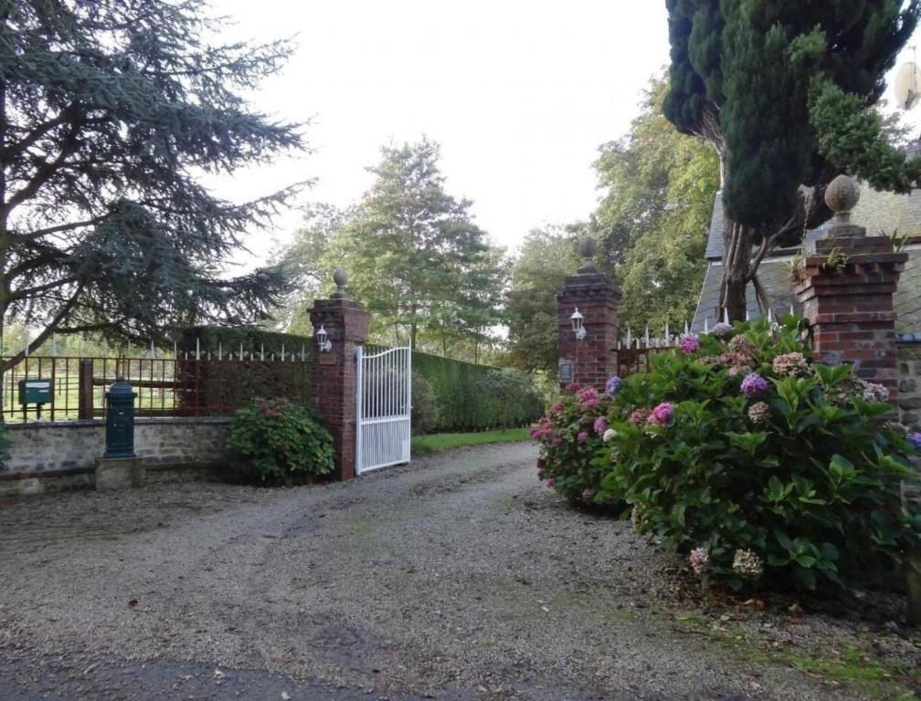 una cerca con una puerta en un patio con flores en Ferme de Dauval, en Mandeville-en-Bessin
