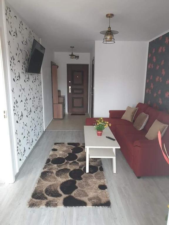 a living room with a red couch and a table at Apartament Alina in Saturn