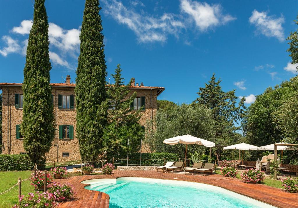 a pool in front of a building with trees and umbrellas at Tenuta Santa Trice in Riotorto
