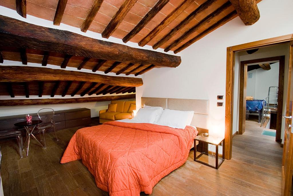 a bedroom with a bed with an orange comforter at Vicolo dell'Oste in Montepulciano
