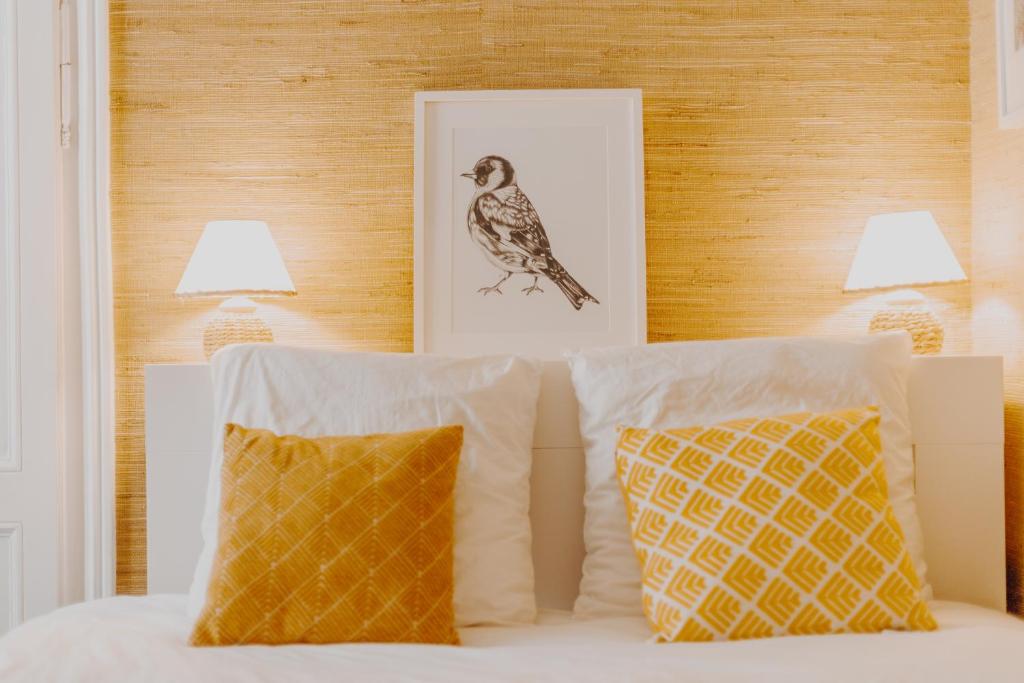 a bed with two pillows and a picture of a bird at L'échappée in Bourges