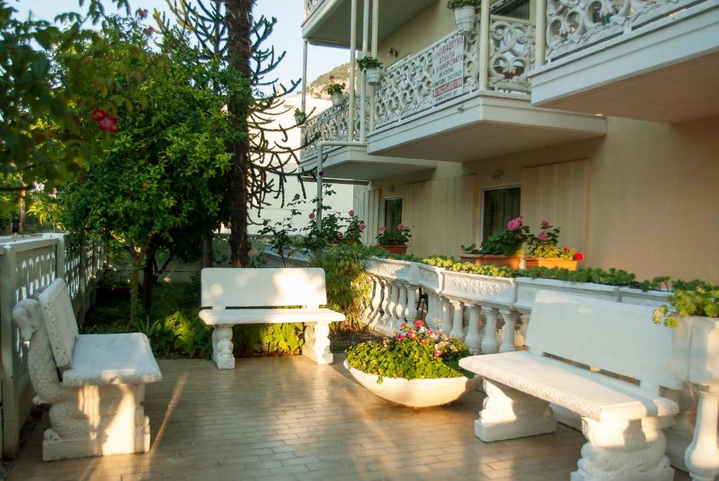 - un patio avec des bancs blancs et des fleurs dans un bâtiment dans l'établissement RONZI APARTMANT, à Kamena Vourla