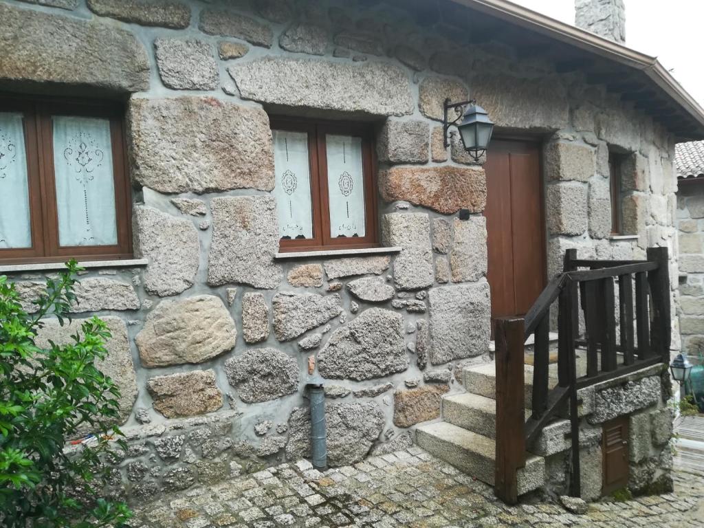 a stone house with a wooden door and windows at Melodia do Campo in Terras de Bouro