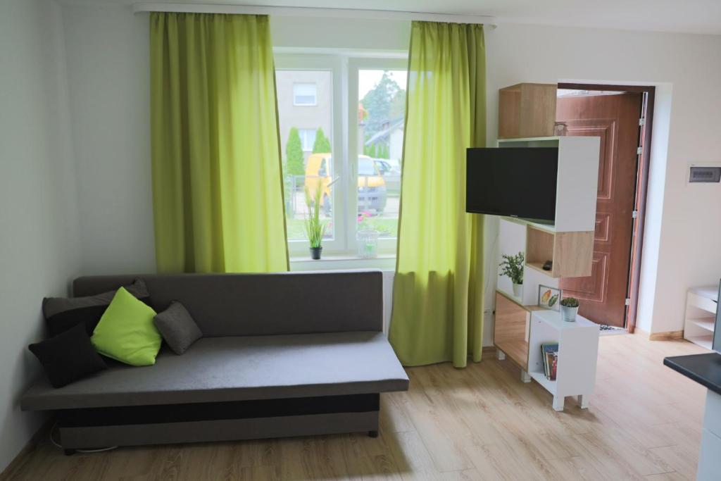 sala de estar con cortinas verdes y sofá en Cienisty Zakątek, en Augustów