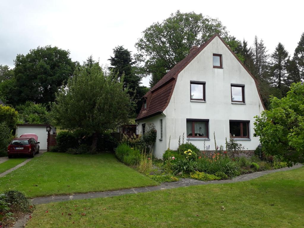 a white house with a car parked in the yard at Ferienwohnung Pries in Kiel