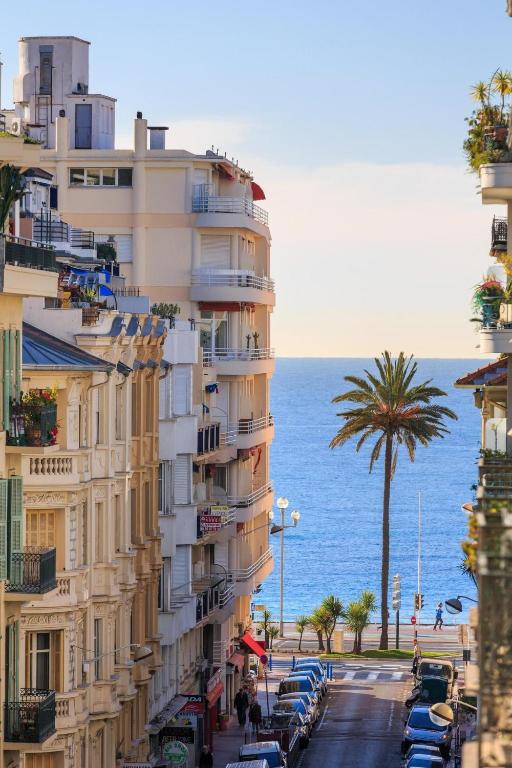 un grand bâtiment à côté de l'océan avec un palmier dans l'établissement LE CLIO CARRÉ D'OR BEACH APARTMENT, à Nice