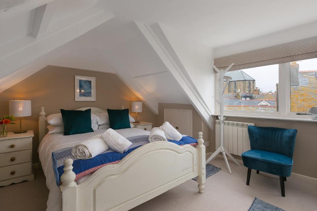 セント・アイヴスにあるAnchorage Guest House, St Ivesの白いベッドと青い椅子のある寝室