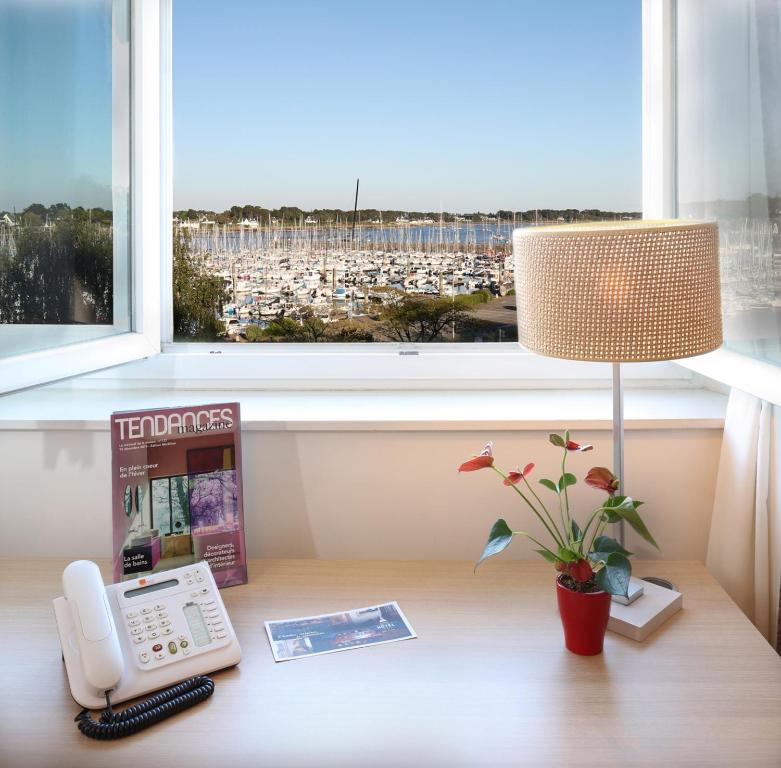a desk with a telephone and a window at Trinite Hotel in La Trinité-sur-Mer