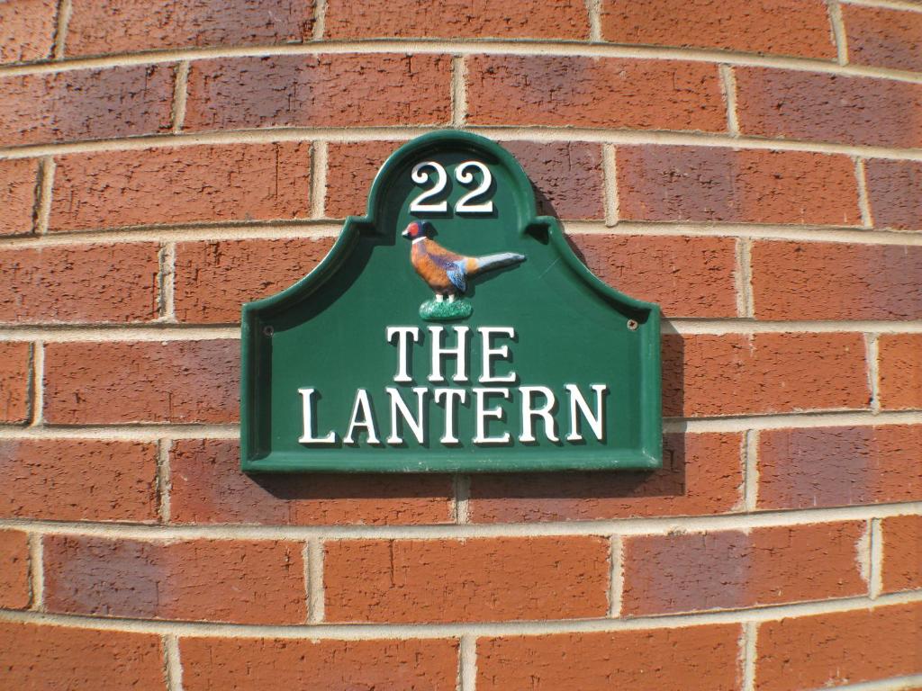 a sign for the lantern hanging on a brick wall at The Lantern in Donaghadee