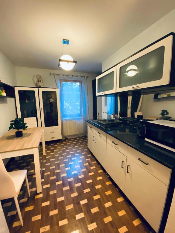 uma cozinha com armários brancos, uma mesa e um micro-ondas em City Centre Apartment em Reghin