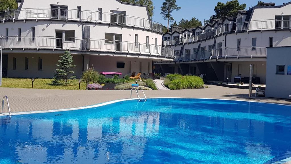 une grande piscine bleue en face d'un bâtiment dans l'établissement Apartament Agnmar Pobierowo, à Pobierowo