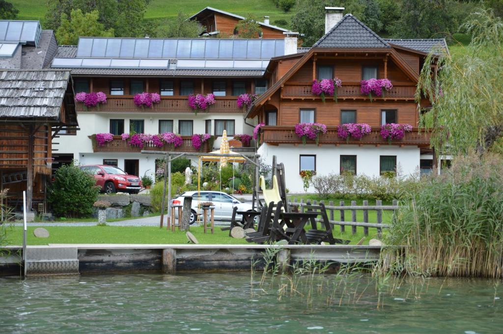 a house next to the water in front of a house at Haus Binter in Weissensee