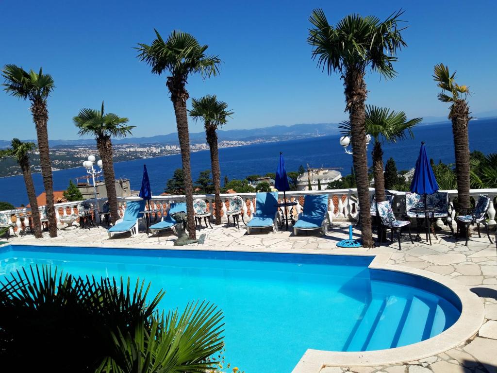 uma piscina num resort com palmeiras e cadeiras em Apartments Darijana em Opatija