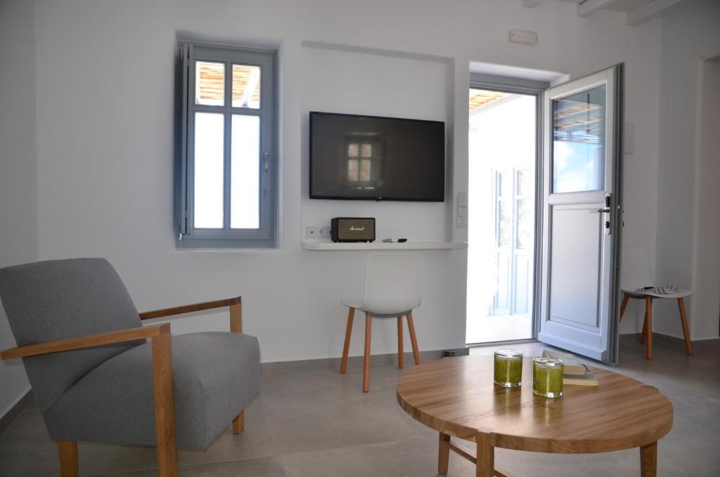 ein Wohnzimmer mit einem Tisch und einem TV an der Wand in der Unterkunft Vorina Ktismata in Amorgós