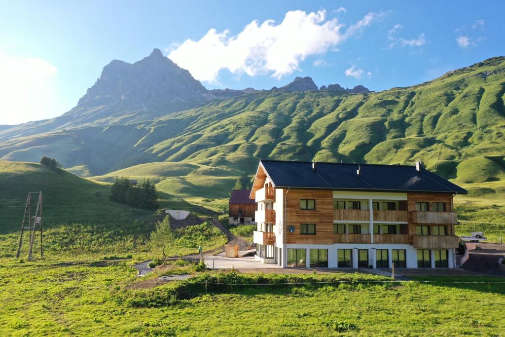 a house on a hill with mountains in the background at apart-wolf-arlberg in Warth am Arlberg