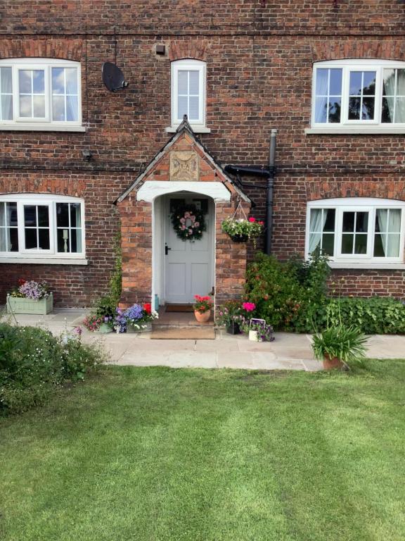 Birtles Farm Bed and Breakfast في كنوتسفورد: منزل من الطوب مع باب أبيض وساحة