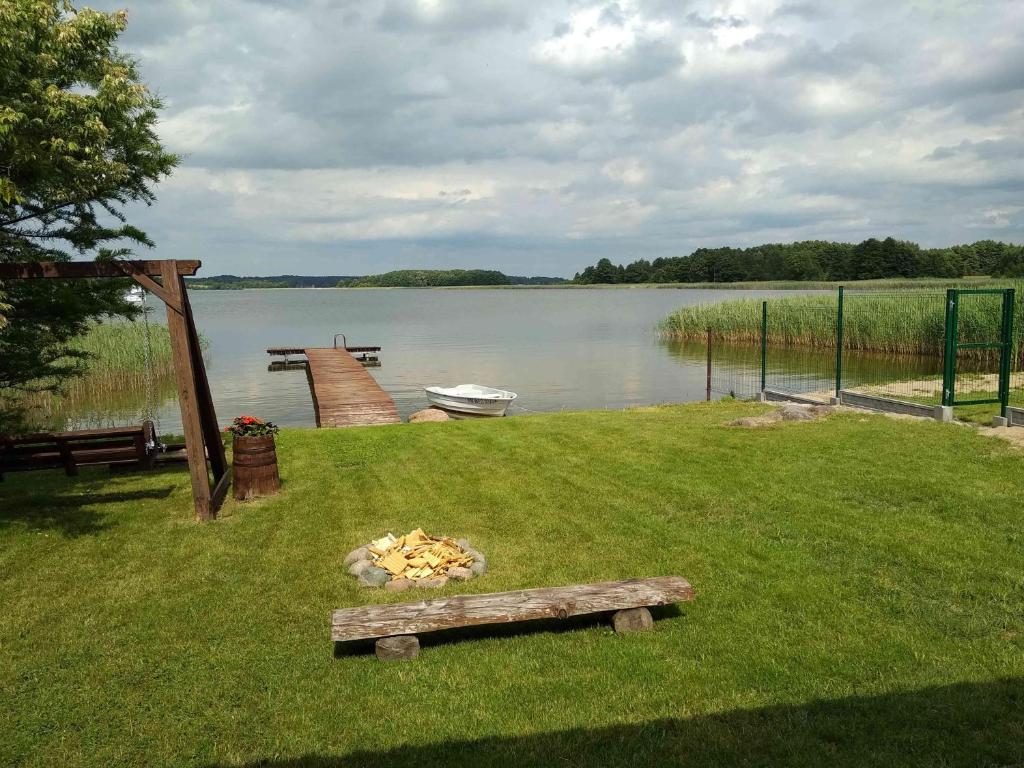 a park bench in the grass next to a lake at Dar Kalu Małgosia in Kal
