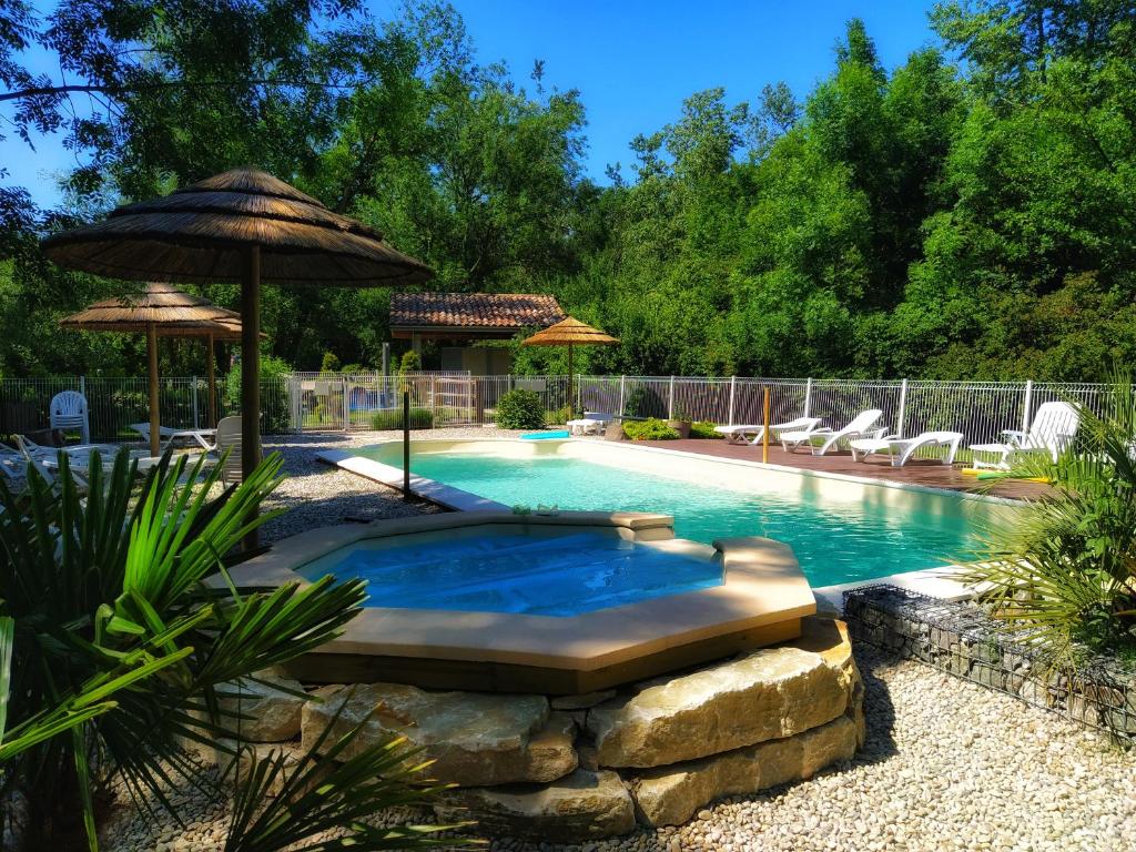 - une piscine avec un parasol et des chaises dans l'établissement Aventure Evasion, à Chatuzange-le-Goubet